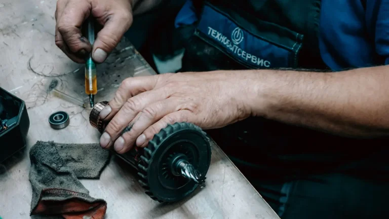 Technician's hands repairing a drive gear, garage door opener repair