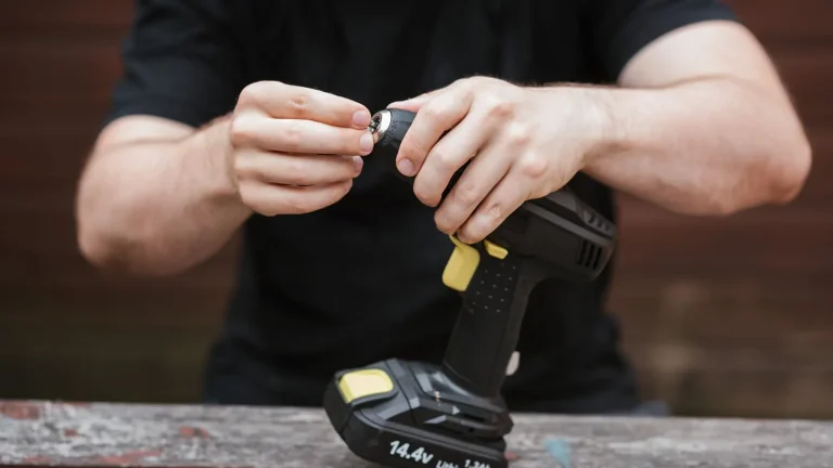 Hands fitting a battery to a drill before a garage door opener installation