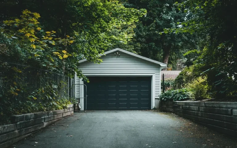 Detached garage with a dark door among trees in Lascassas, TN